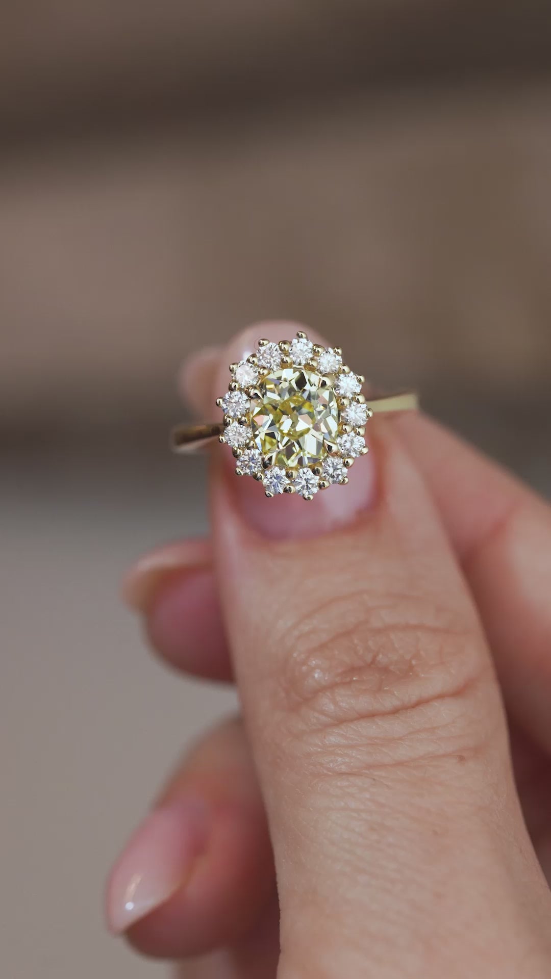 A close-up video of the yellow diamond engagement ring held between fingers, capturing the sparkle of the central diamond and surrounding halo.
