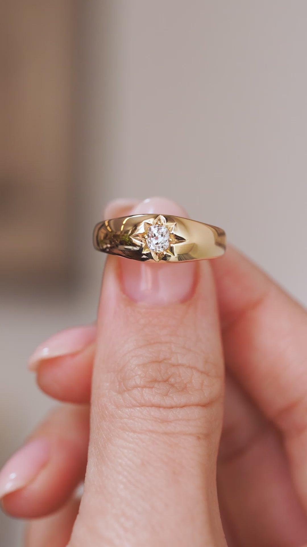 Video close-up of the Victorian ring balanced on a fingertip, showing the flush-set diamond and sculptural gold band.