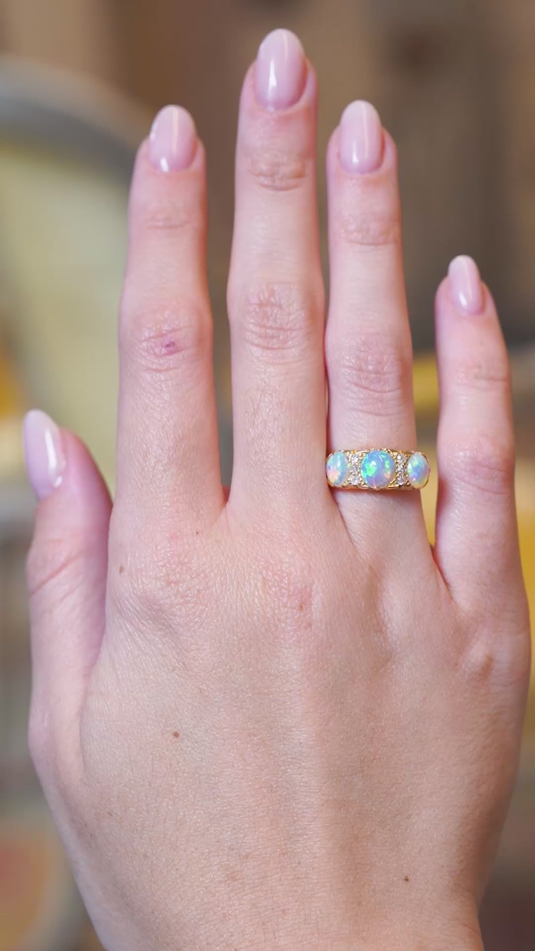 Antique Edwardian opal and diamond three-stone ring worn on hand in motion.