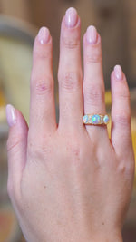Antique Edwardian opal and diamond three-stone ring worn on hand in motion.