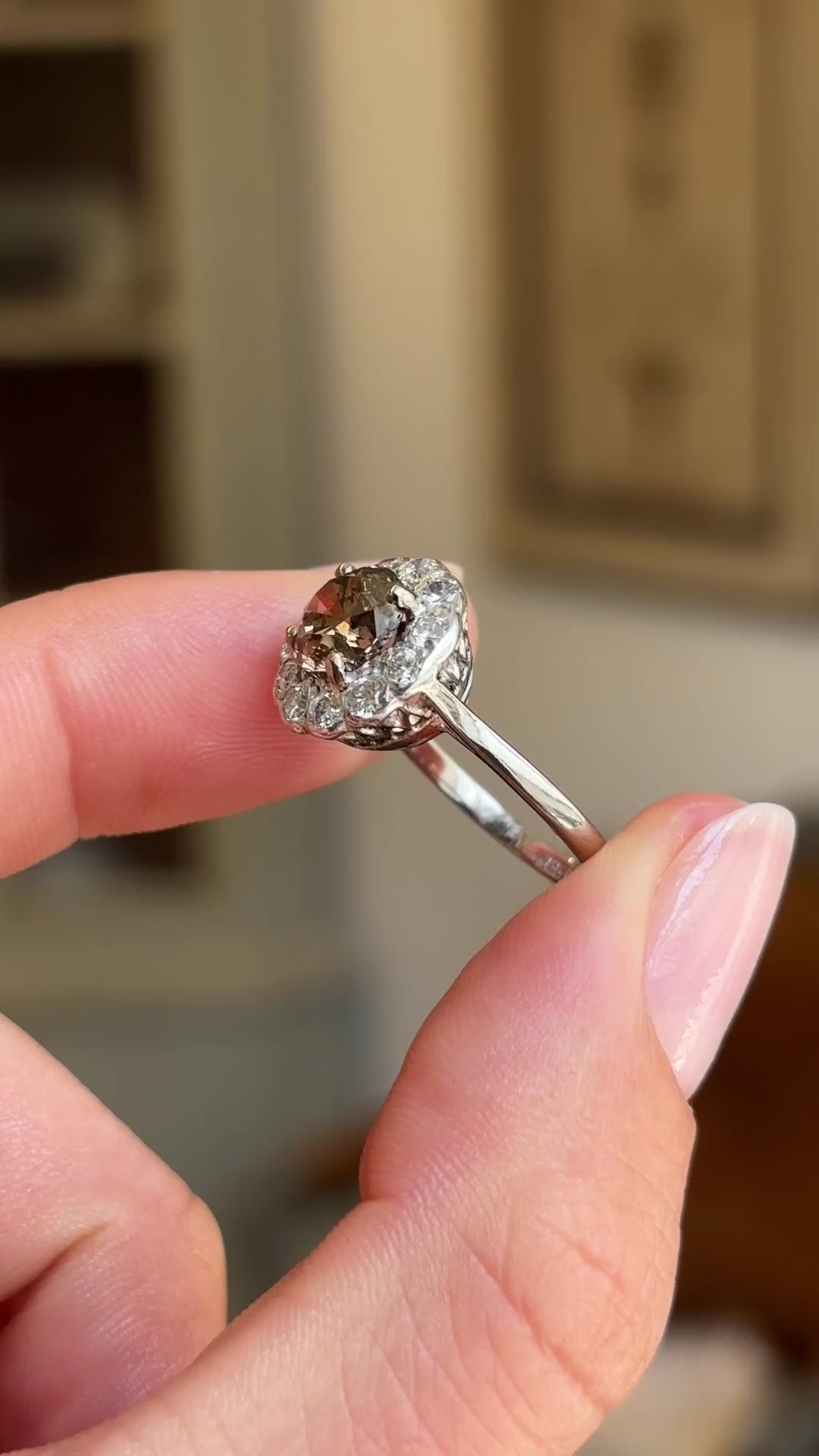 Vintage 1950s cinnamon brown diamond cluster engagement ring featuring a cinnamon brown diamond encircled by sparkling diamonds, held by hand for detailed viewing.