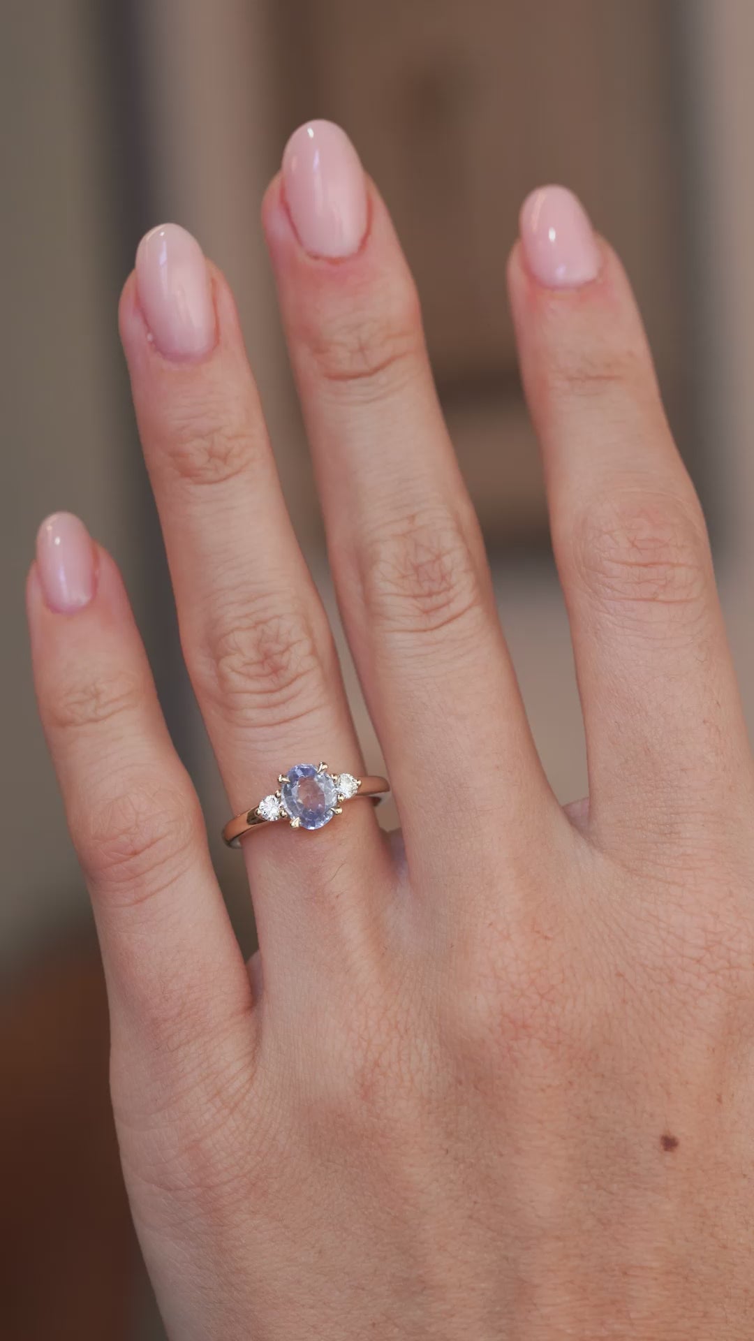 A video of the oval blue sapphire ring worn on a finger, capturing the gemstone's soft blue tones and sparkling diamond shoulders.