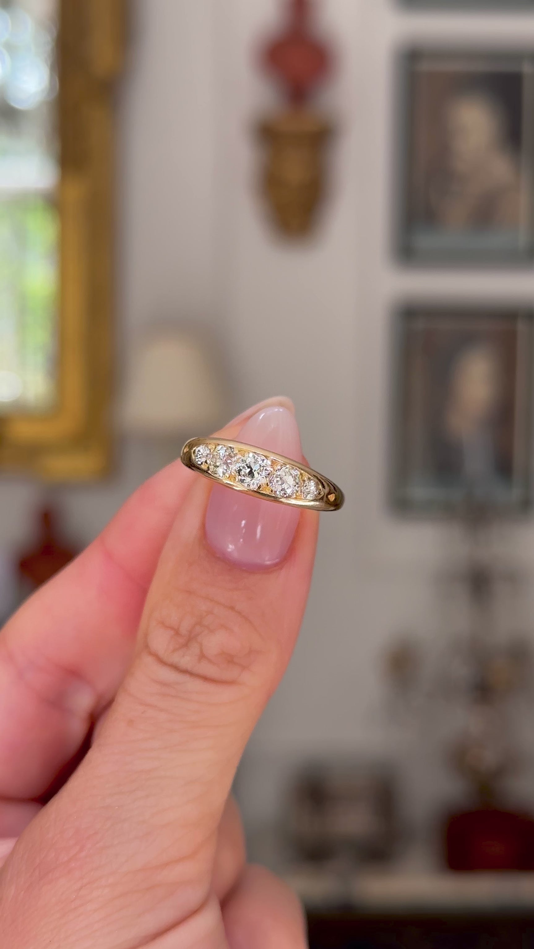 Antique five stone diamond engagement ring, held in fingers and rotated to give perspective, front view.