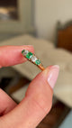 Close up video of a hand holding an Antique, Victorian emerald & old-mine diamond five-stone engagement ring