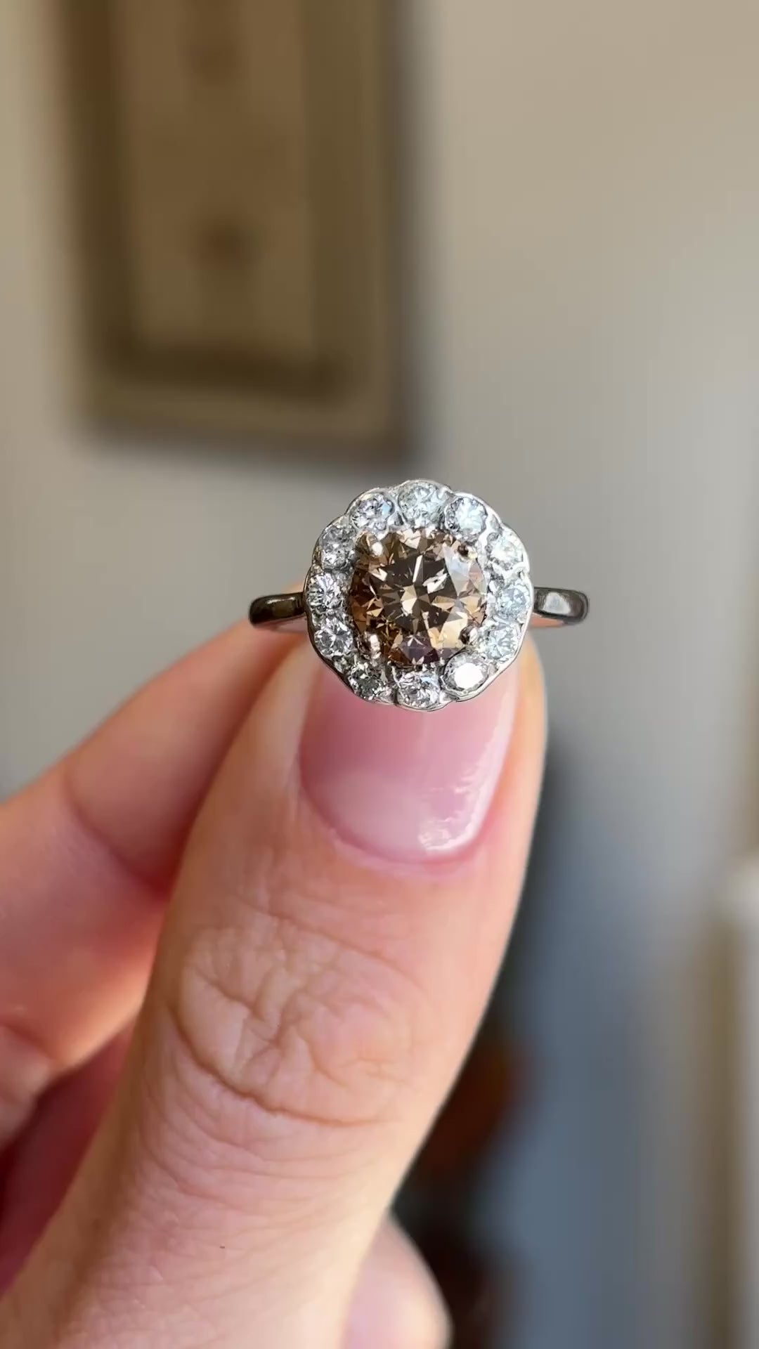 Vintage 1950s cinnamon brown diamond cluster engagement ring showcasing a cinnamon brown diamond centre stone and diamond halo, held by hand to highlight the setting and craftsmanship.
