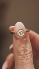 A video of An Antique-inspired, Old-cut diamond solitaire engagement ring mounted in yellow gold held in between the fingers and close to the camera as it is slowly rotated to show off different angles.