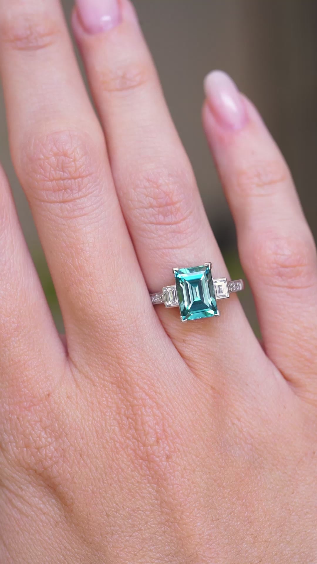 A video of an antique Art Deco 1920s blue zircon and diamond ring shown on the hand.