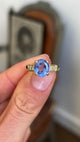 Vintage 1990s sapphire and diamond engagement ring featuring an oval blue sapphire centre stone and diamond-set shoulders, held by hand to showcase the setting and design.