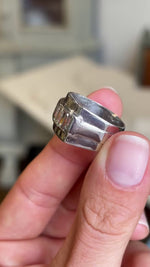 A close up video of a platinum 1940s vintage cocktail ring, channel-set with baguette-cut diamonds, showcasing the side profile of the ring.