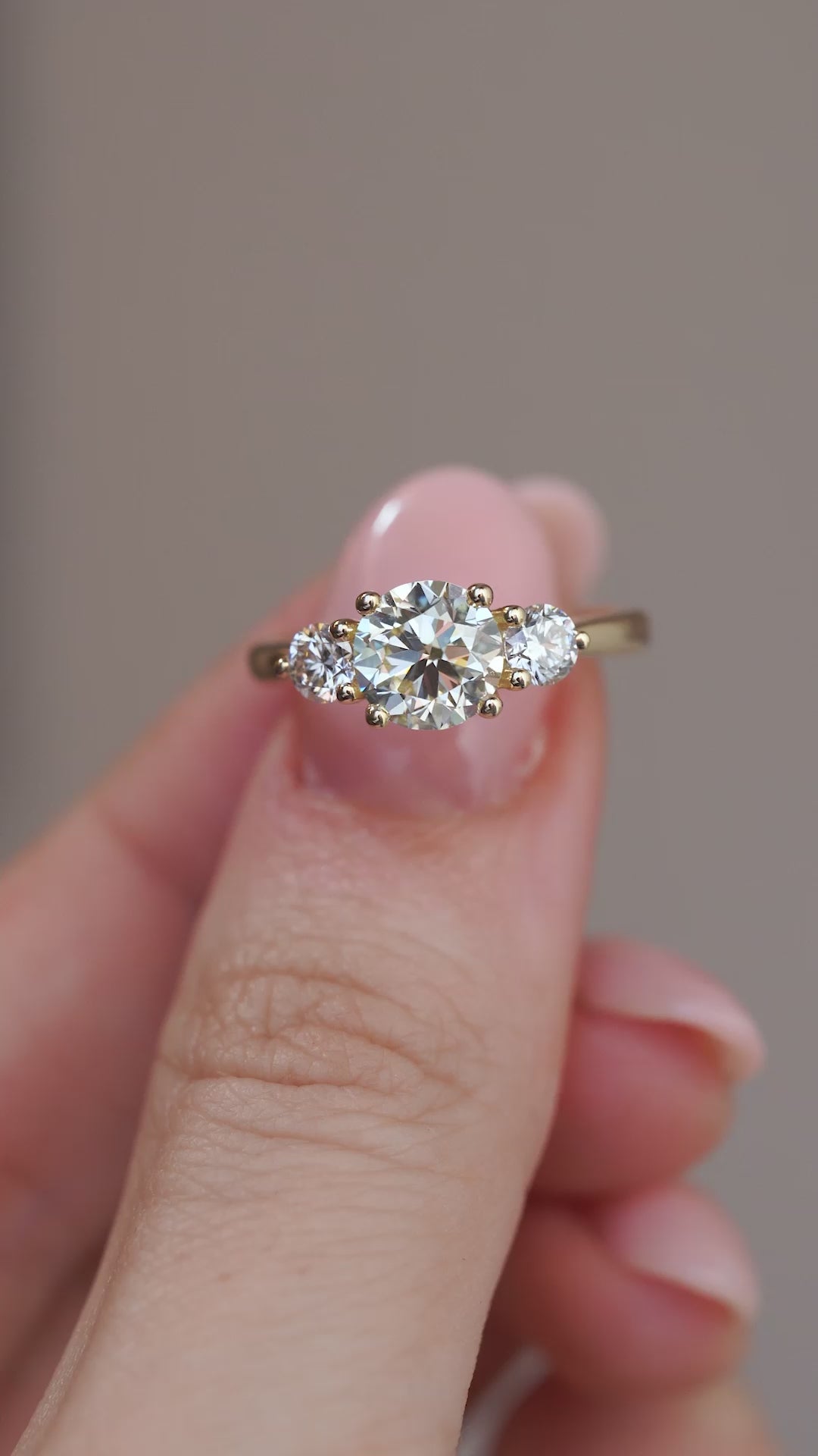 Video close-up of the yellow gold diamond ring held between fingers, showcasing the central stone and its sparkle.