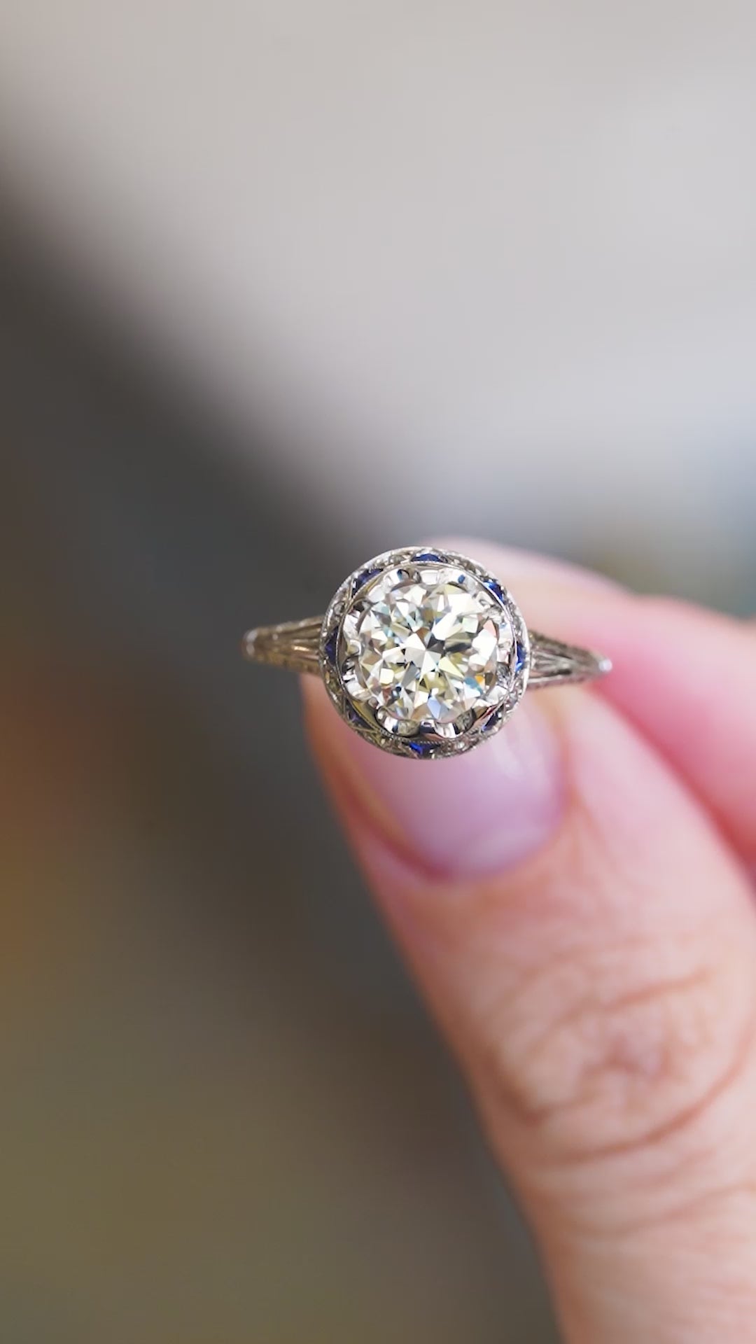 Antique Art Deco ring showing central diamond cluster and sapphire side detail between fingers.