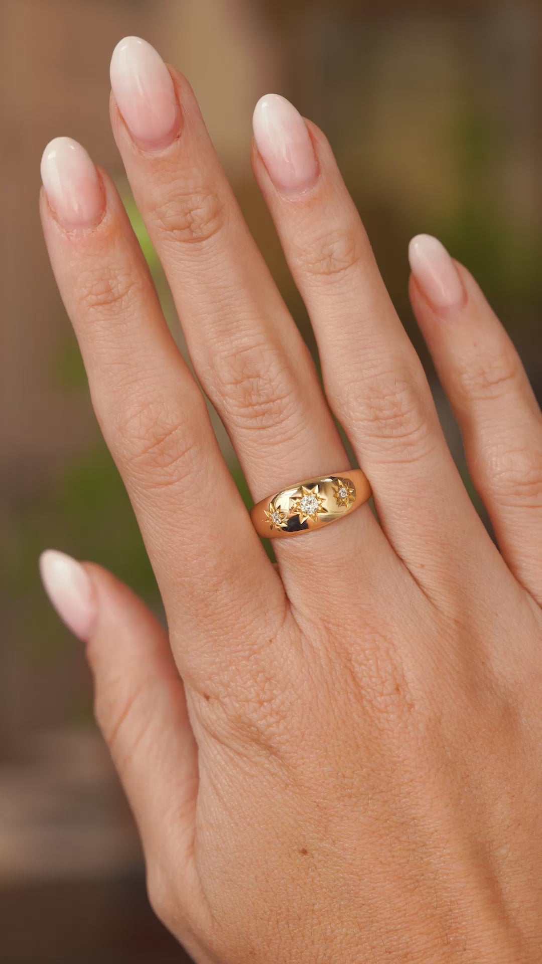 A video of an outstretched hand wearing an antique Edwalton era yellow gold gypsy ring with three old cut diamond set in star settings the hand slowly turns to show off the proportions