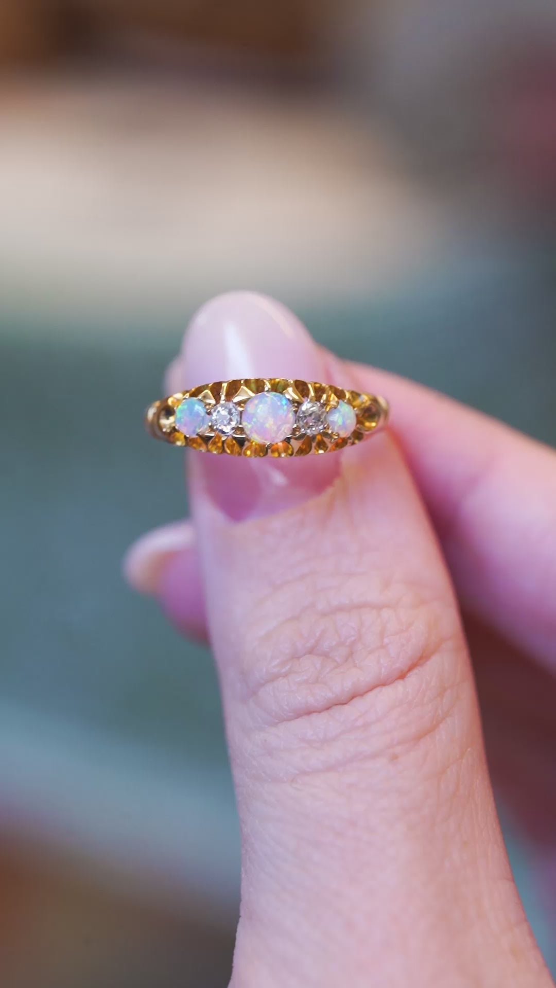 Close detail video of antique opal and diamond five-stone ring with ornate gold setting.