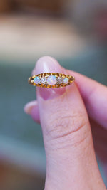 Close detail video of antique opal and diamond five-stone ring with ornate gold setting.