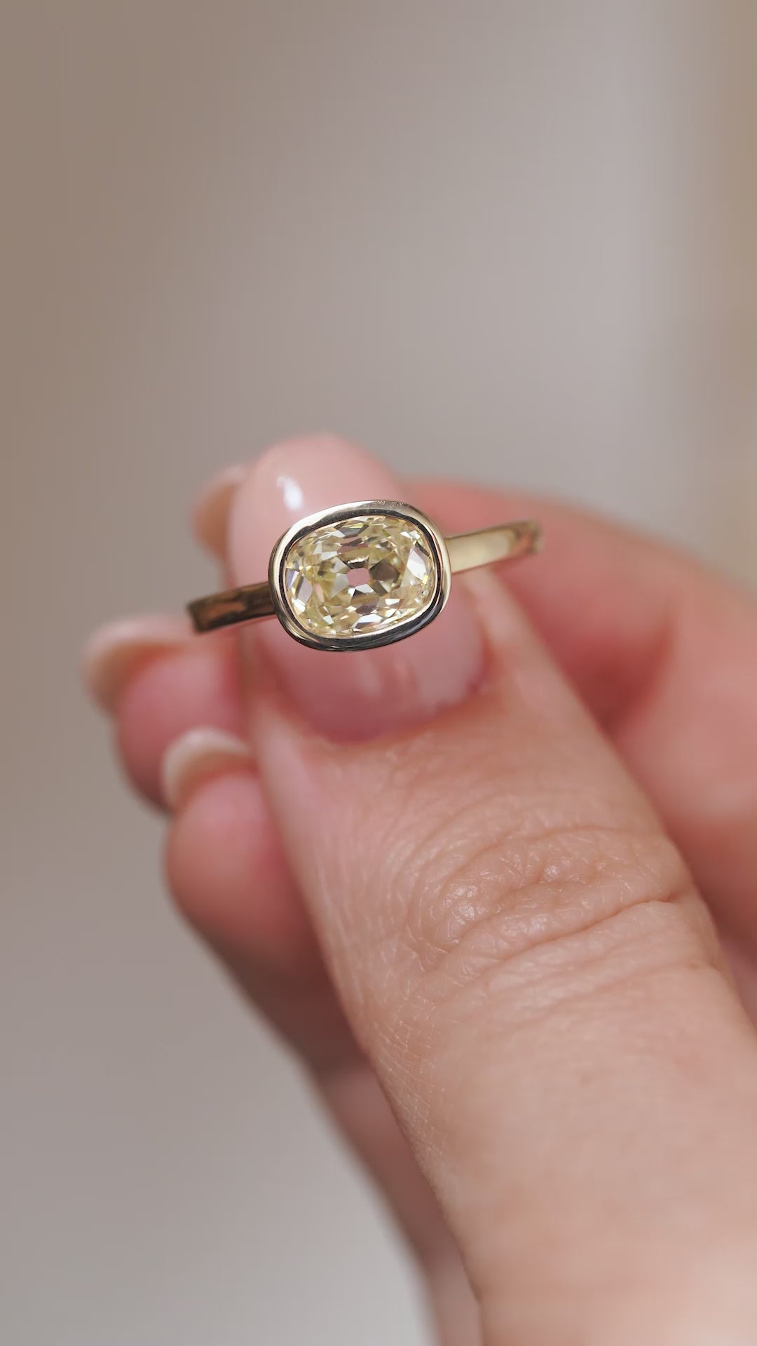 A close-up video of the diamond engagement ring held between fingers, showcasing its distinctive old mine-cut facets and warm colour.