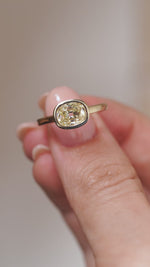 A close-up video of the diamond engagement ring held between fingers, showcasing its distinctive old mine-cut facets and warm colour.