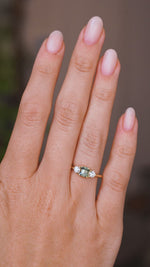 A video of a hand wearing an Antique-inspired, Teal sapphire and diamond three-stone engagement ring in yellow gold.