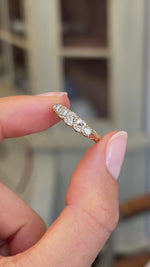 Antique Victorian old-mine diamond five-stone ring featuring five graduated old-mine cut diamonds in a classic carved setting, held by hand for detailed viewing.