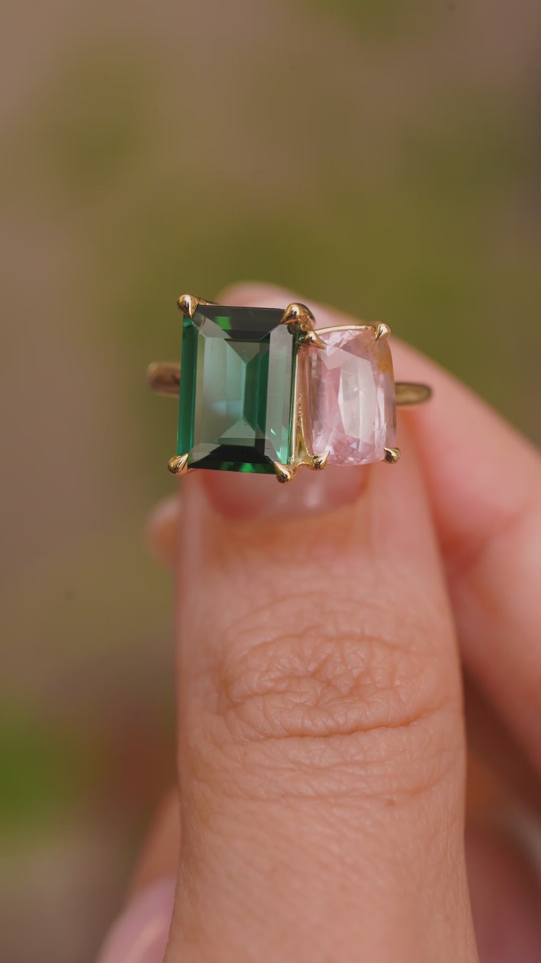 A video of Vintage-inspired, Green tourmaline and pink sapphire Toi et Moi engagement ring in yellow gold held between the fingers and rotated to show different angles.