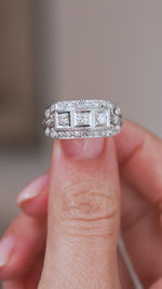 Video of the Art Deco diamond cluster ring balanced on a fingertip, highlighting its broad geometric face and platinum detailing.