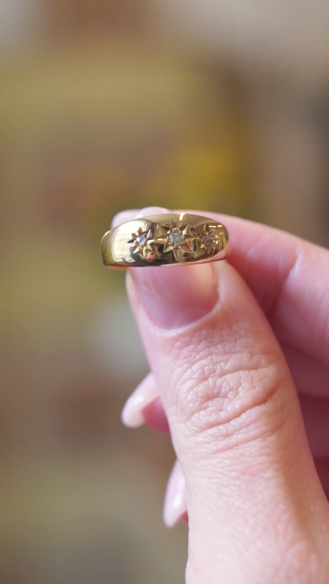 Close detail video of antique Edwardian three-stone diamond gypsy ring with star-set diamonds between fingers.