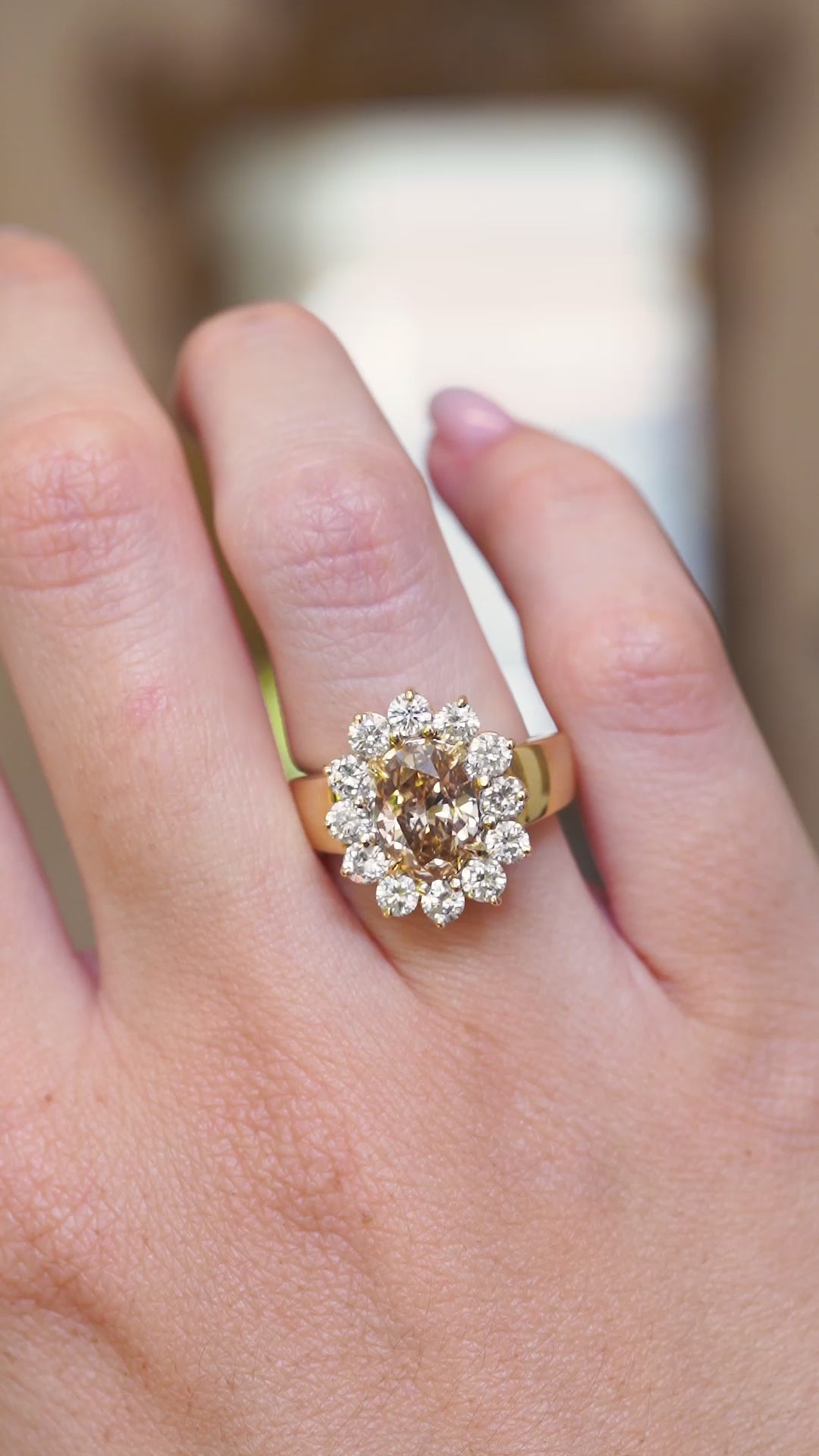 A close up video of a vintage brown diamond cocktail ring with a diamond halo worn on the hand.