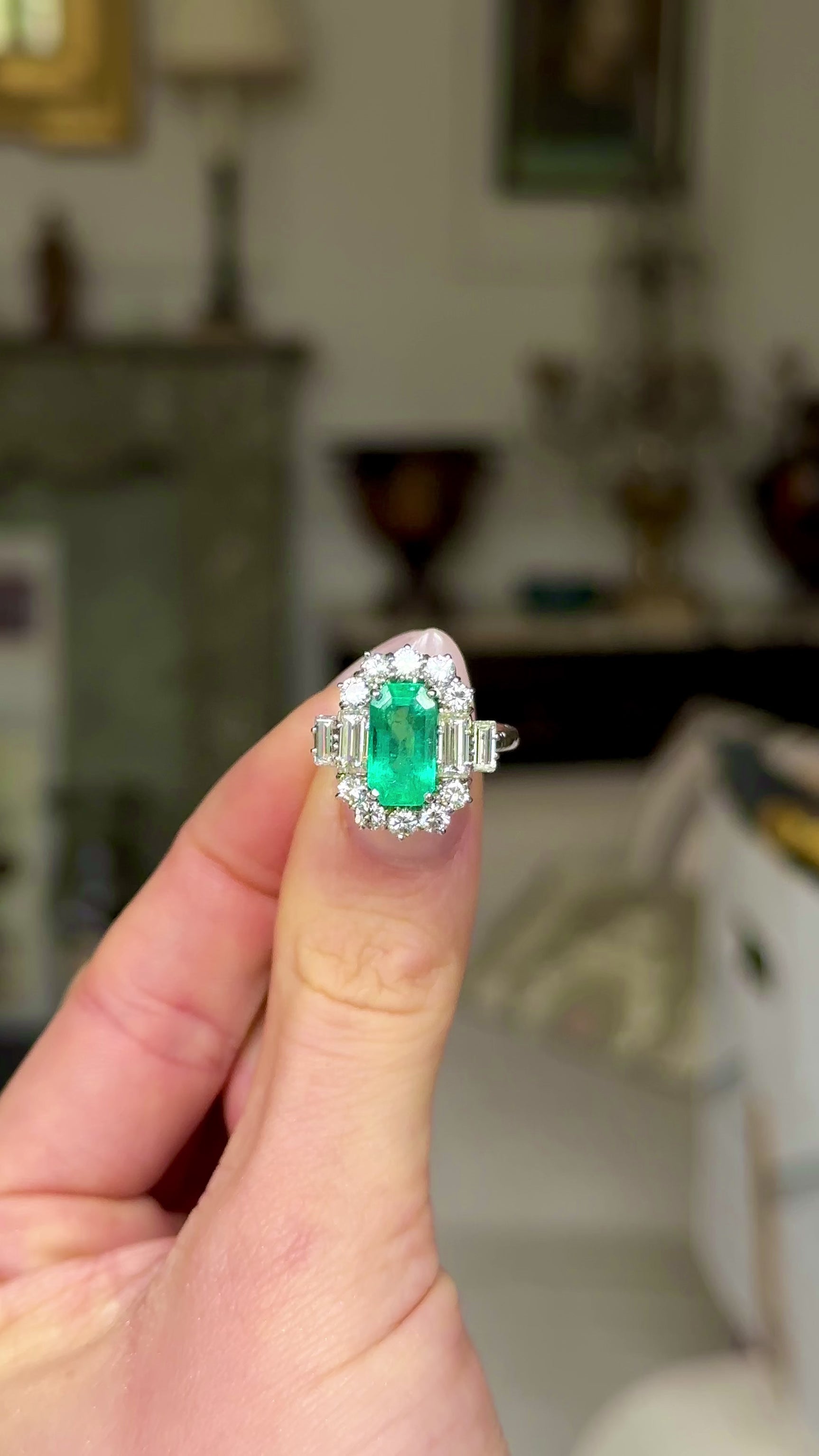 Vintage emerald and diamond cluster ring, held in fingers and moved around to give perspective.