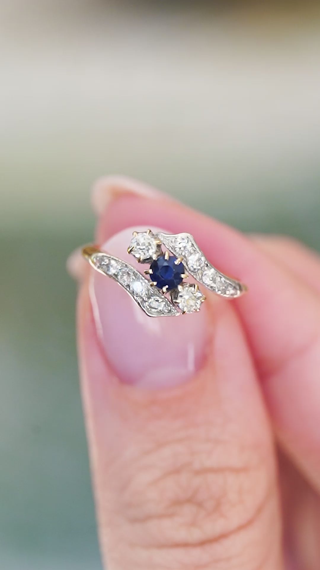 Edwardian sapphire and diamond twist ring balanced on fingertip