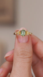 Video close-up of the vintage-style ring balanced on a fingertip, highlighting the sapphire and ornate gold work.