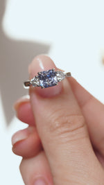 A close-up video of the platinum sapphire ring held between fingers, showcasing the gemstone's facets and sparkling diamond shoulders.