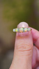 A close-up of an antique opal and diamond half-hoop ring in yellow gold shown in video between fingers. 
