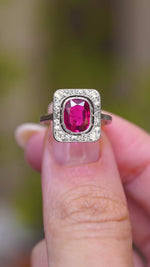 A video of an antique red spinel and diamond cluster ring held between the fingers showcasing the ring details.