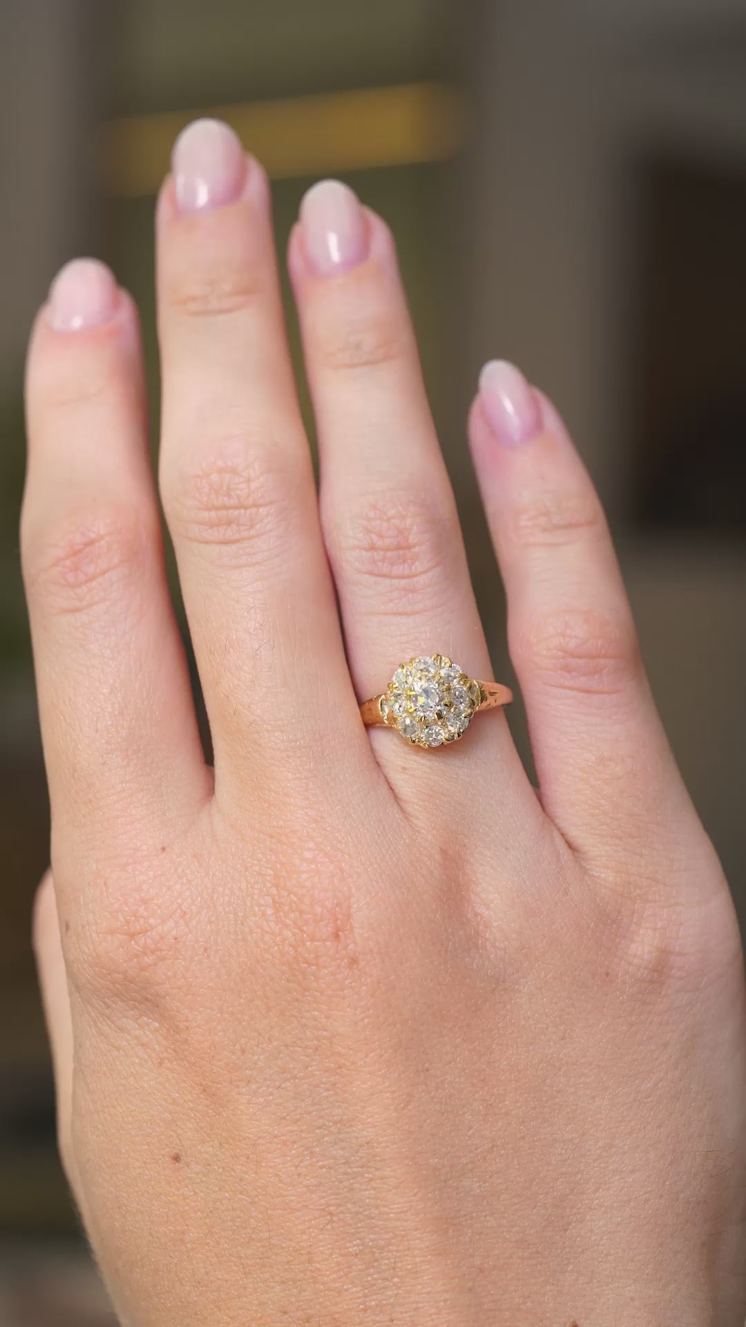 A video of a hand wearing an antique diamond cluster engagement ring in yellow gold and shown from a distance with hand outstretched to display the scale of the ring as the hand is slowly turned.