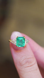 Vintage 1970s ring showing emerald cut centre and diamond side stones between fingers.
