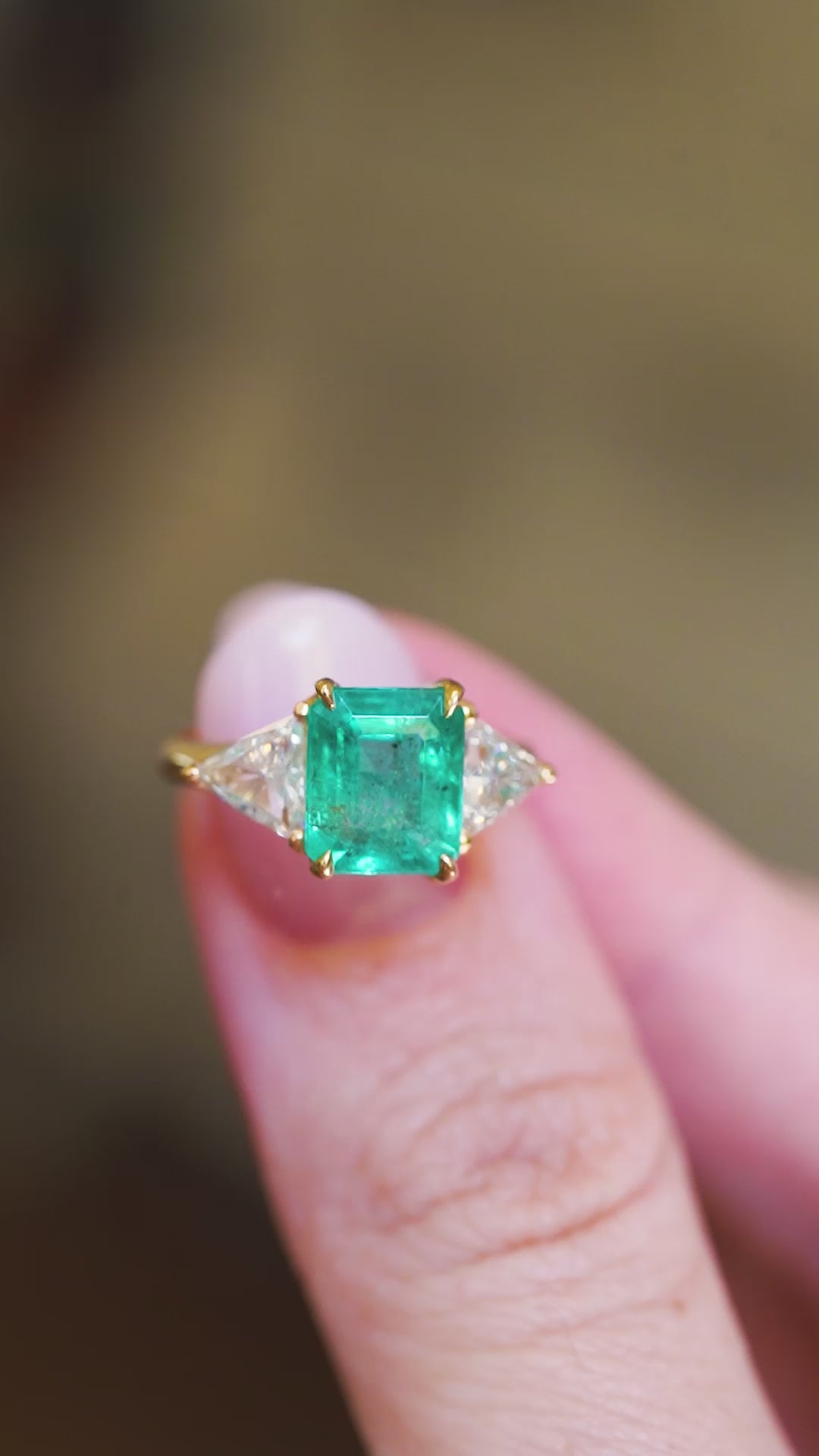 Vintage 1970s ring showing emerald cut centre and diamond side stones between fingers.