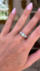 Opal and diamond three stone ring, worn on hand and moved away from lens to give perspective,front view. 