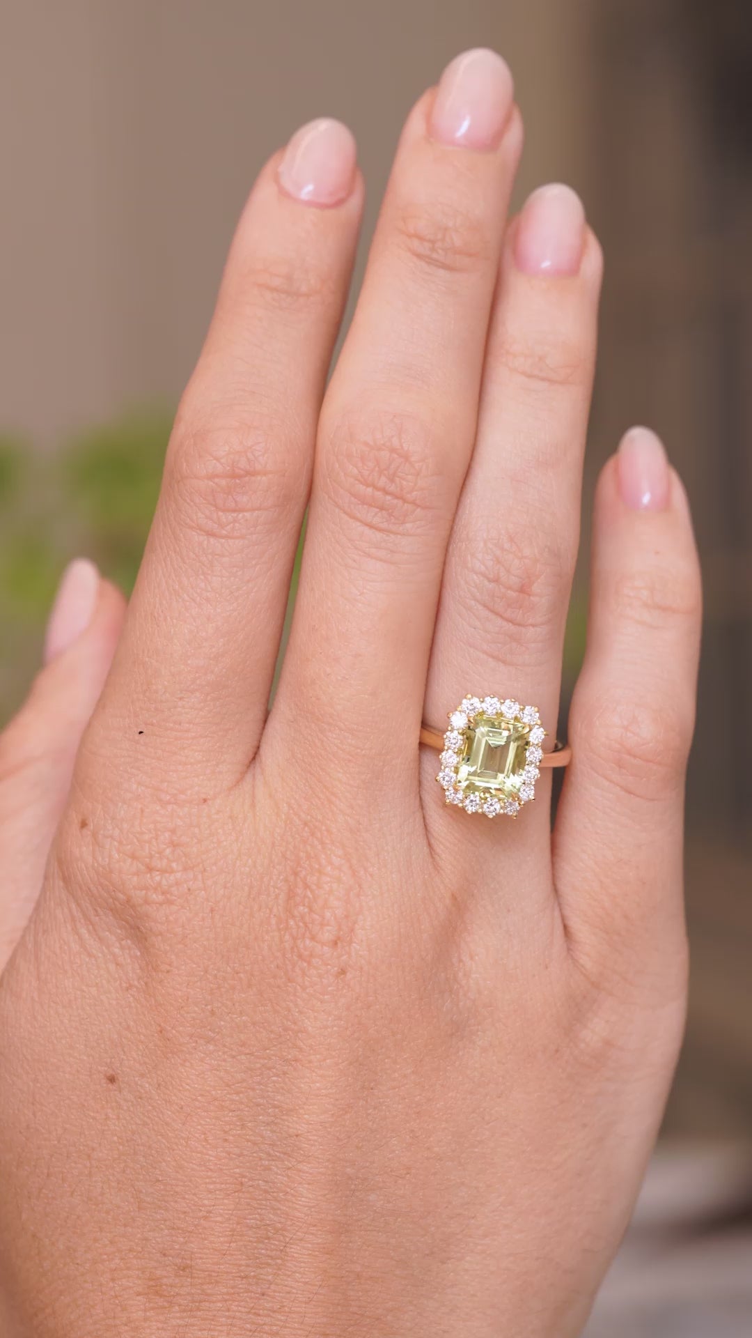 A video of an Antique-inspired, Green beryl and diamond cluster engagement ring worn on a persons hand and slowly rotated to showcase the low profile of the ring once worn and the yellow gold band.
