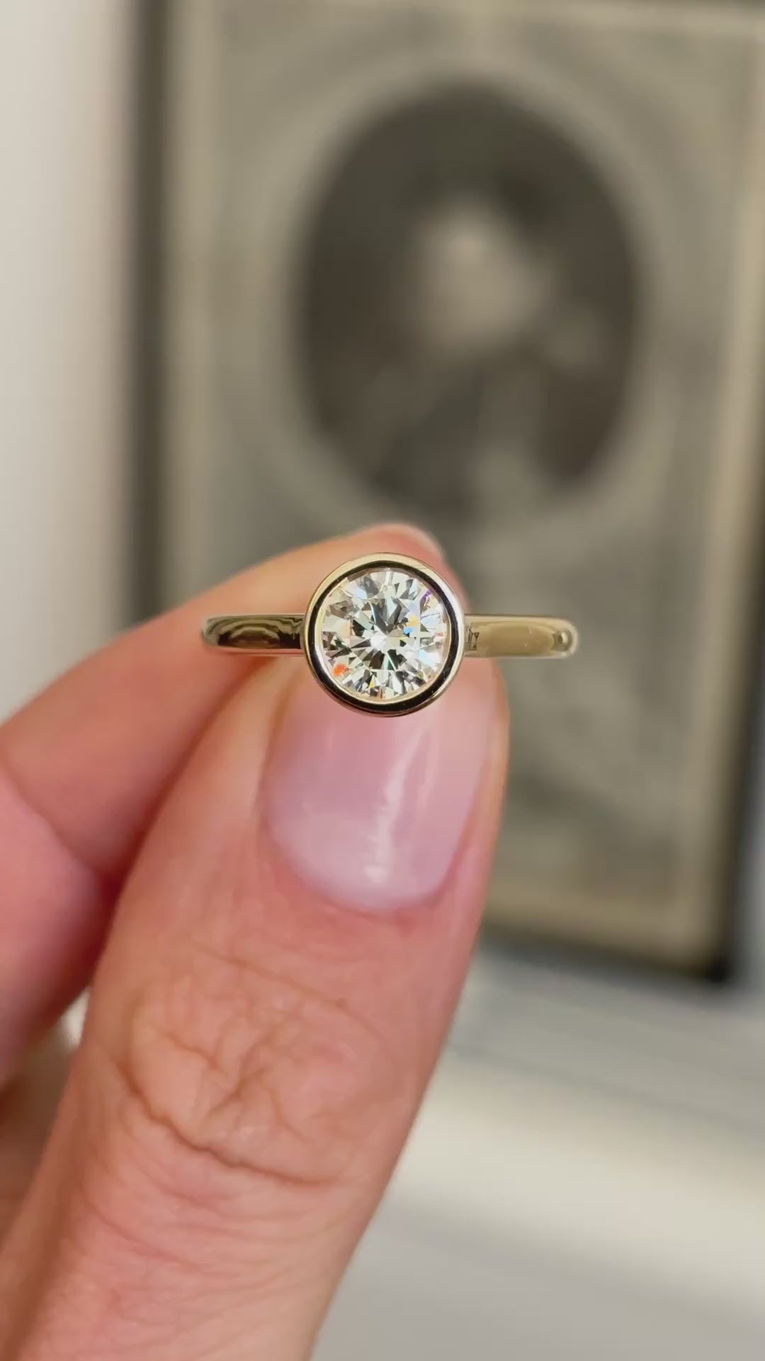 Vintage inspired diamond rub-over solitaire engagement ring showcasing a round brilliant-cut diamond in a classic rub-over setting, held by hand to highlight the craftsmanship and design.