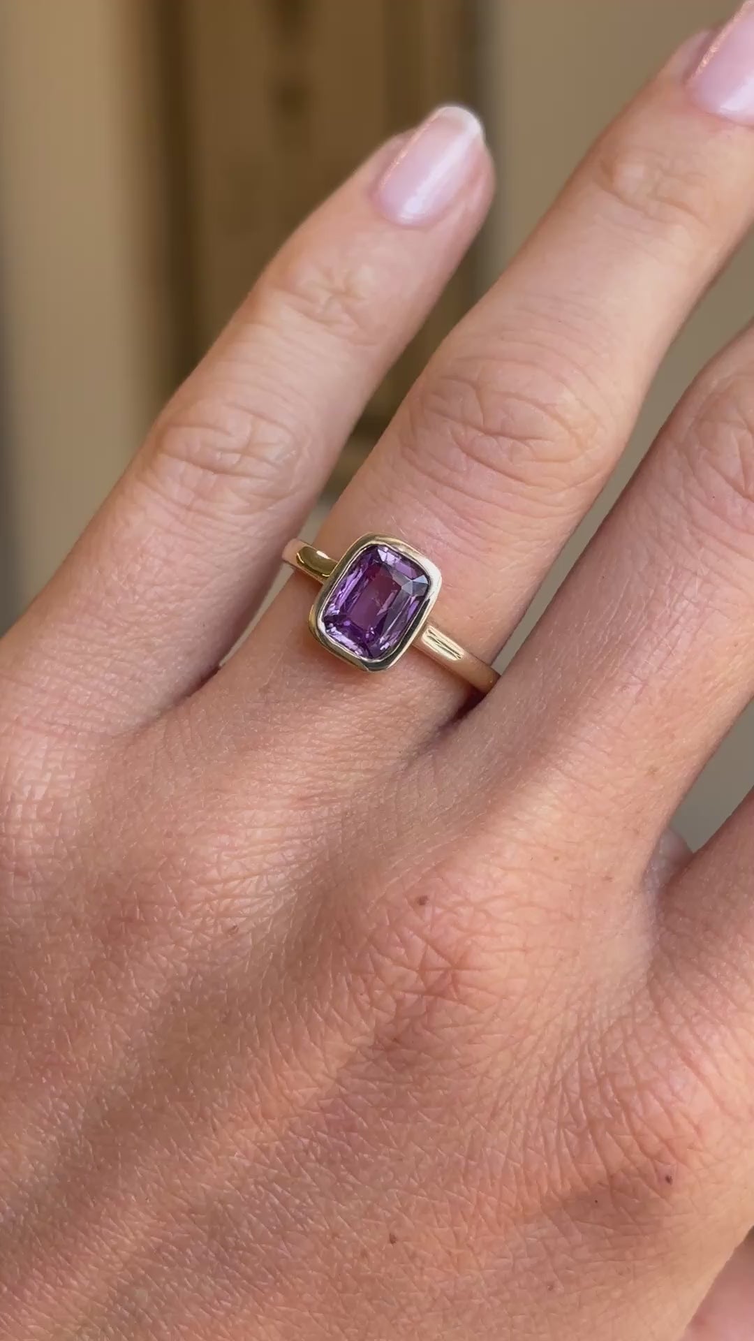 Royal purple cushion-cut sapphire solitaire engagement ring featuring a cushion-cut purple sapphire in a classic solitaire setting, displayed on a hand.
