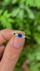 Antique, Edwardian sapphire and diamond three-stone ring held in fingers.
