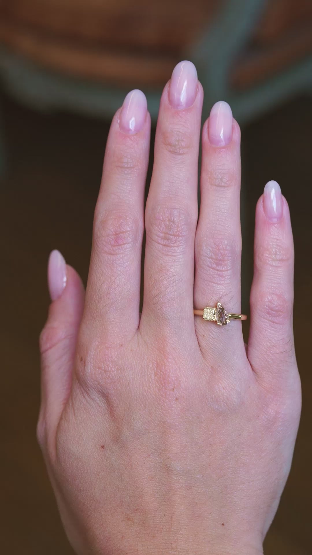 Brown and yellow diamond Toi et Moi engagement ring worn on hand with gold band with subtle motion.