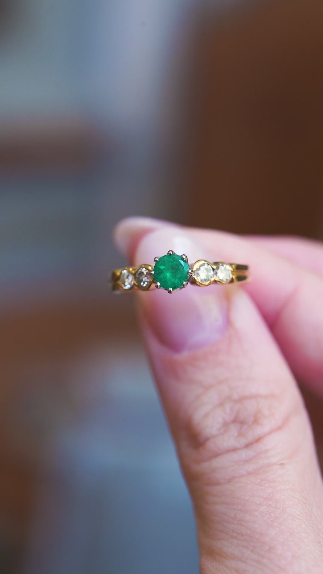 Emerald and diamond five stone ring shown in close detail.