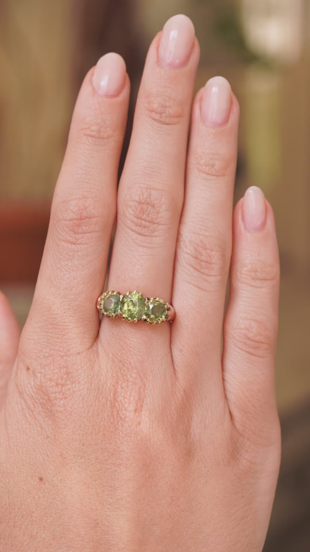 A video of an antique trilogy green zircon gold ring in gold metal worn on the hand and shown from a distance to display scale of ring.