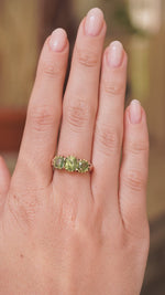 A video of an antique trilogy green zircon gold ring in gold metal worn on the hand and shown from a distance to display scale of ring.