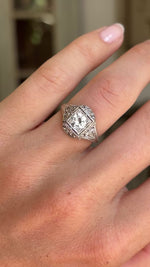 Antique Art Deco diamond cluster ring with intricate openwork detailing and diamond set geometric cluster, featured on a hand.