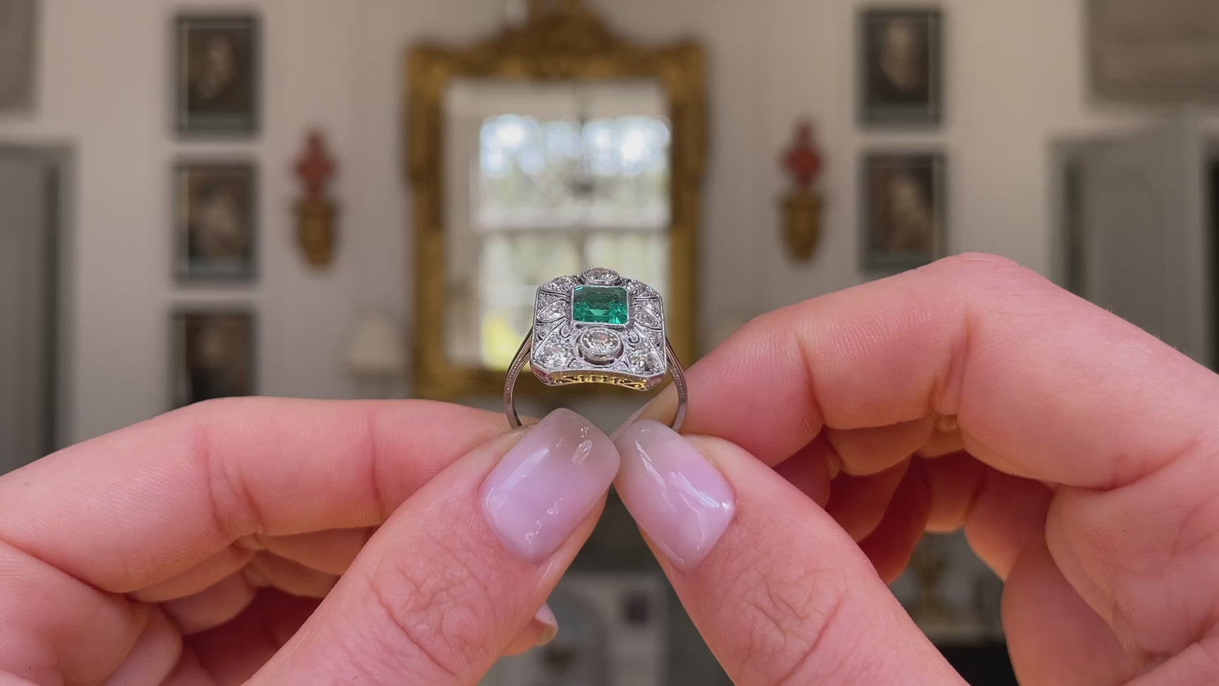 Art Deco emerald and diamond panel ring, held in fingers and rotated to give perspective.