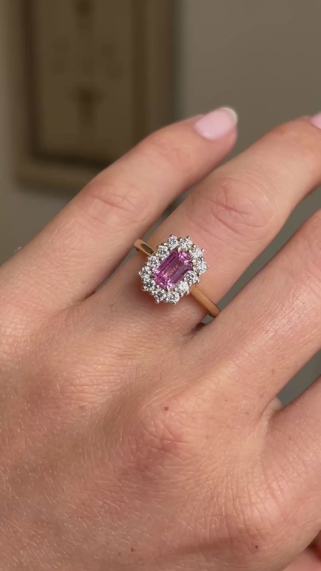A close-up video of an Antique-inspired, pink sapphire and diamond cluster engagement ring worn on a hand.