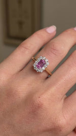 A close-up video of an Antique-inspired, pink sapphire and diamond cluster engagement ring worn on a hand.