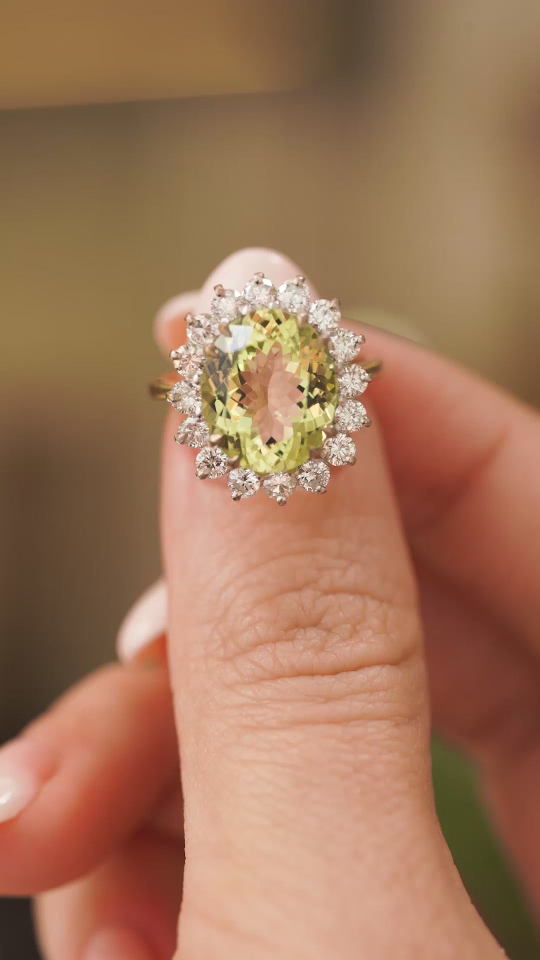 A video of a Vintage, 1960s Green beryl and diamond cluster engagement ring in yellow gold held between the fingers and slowly rotated showing off different angles of the ring.