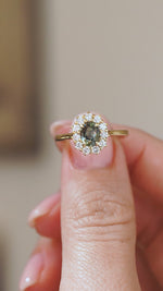Video close-up of an antique-inspired green sapphire cluster ring balanced on a fingertip, capturing the diamonds’ movement and sparkle.